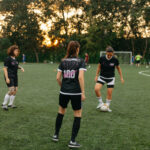Women soccer players practicing on a field at sunset