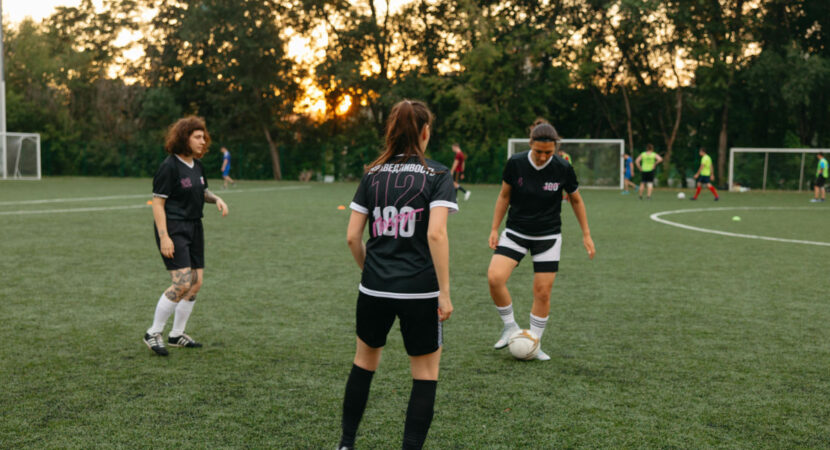 Women soccer players practicing on a field at sunset