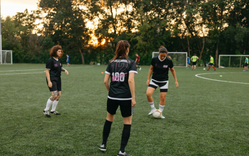 Women soccer players practicing on a field at sunset