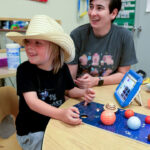 Speech language pathologist playing with kid during Project MESA summer camp.