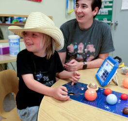 Speech language pathologist playing with kid during Project MESA summer camp.