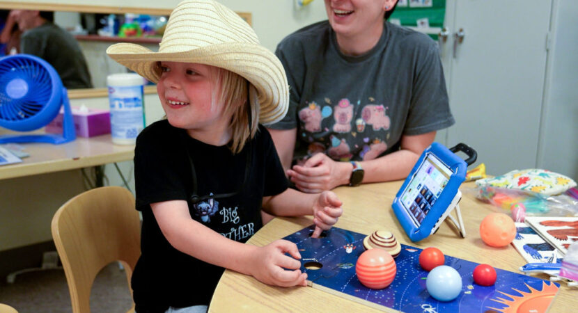 Speech language pathologist playing with kid during Project MESA summer camp.