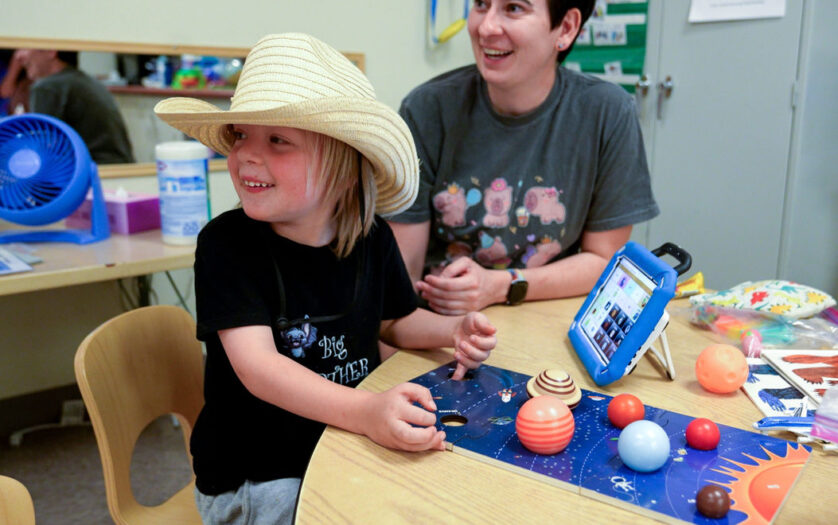 Speech language pathologist playing with kid during Project MESA summer camp.