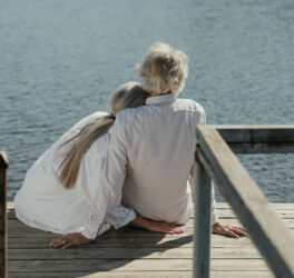 A senior couple enjoys a peaceful moment sitting together on a wooden dock by the lake
