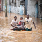 People navigating a flooded street, showcasing resilience amidst natural disaster in Africa.