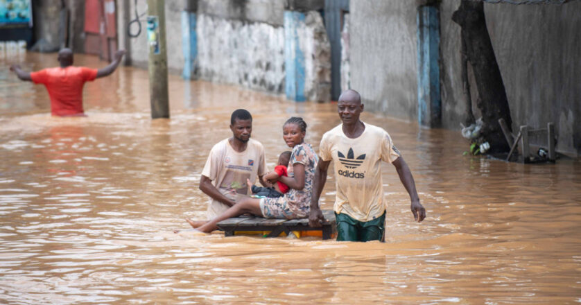 People navigating a flooded street, showcasing resilience amidst natural disaster in Africa.