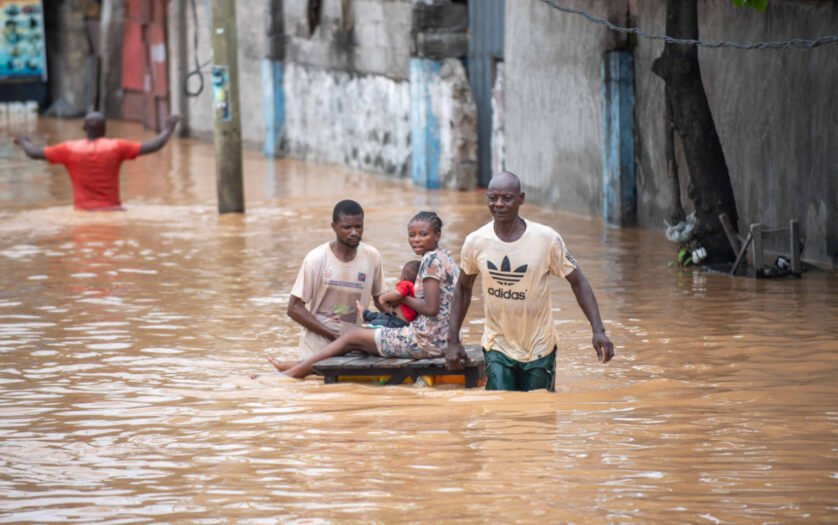 People navigating a flooded street, showcasing resilience amidst natural disaster in Africa.
