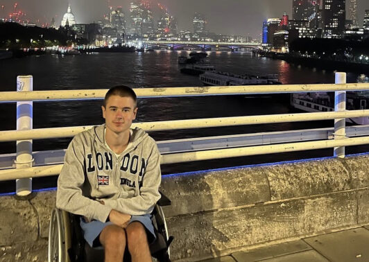 Liam Virgo in his wheelchair on a footbridge, London